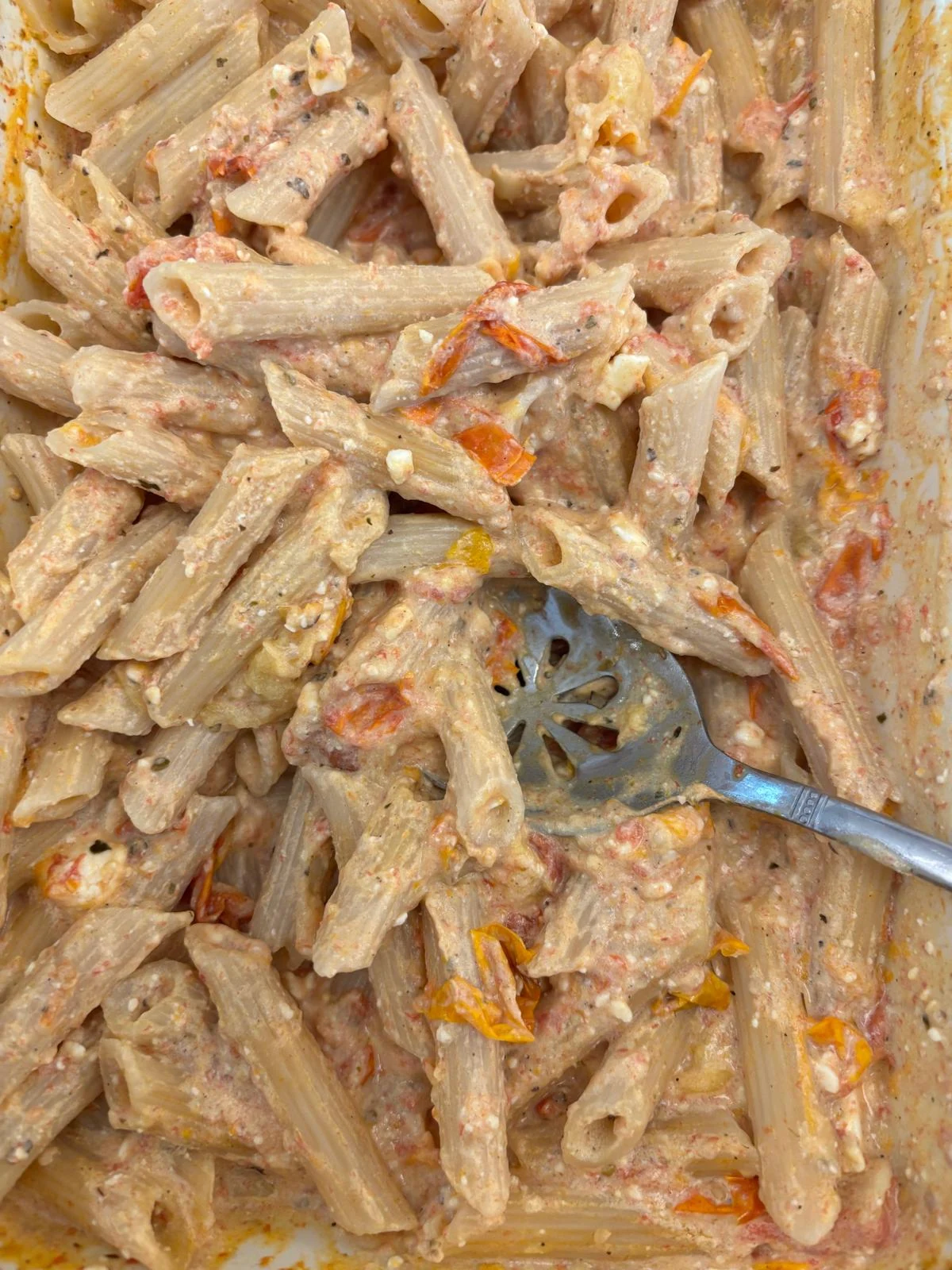 Penne tossed in pale creamy sauce with red/yellow roasted tomato skins; companion 041 shows the feta-tomato base.