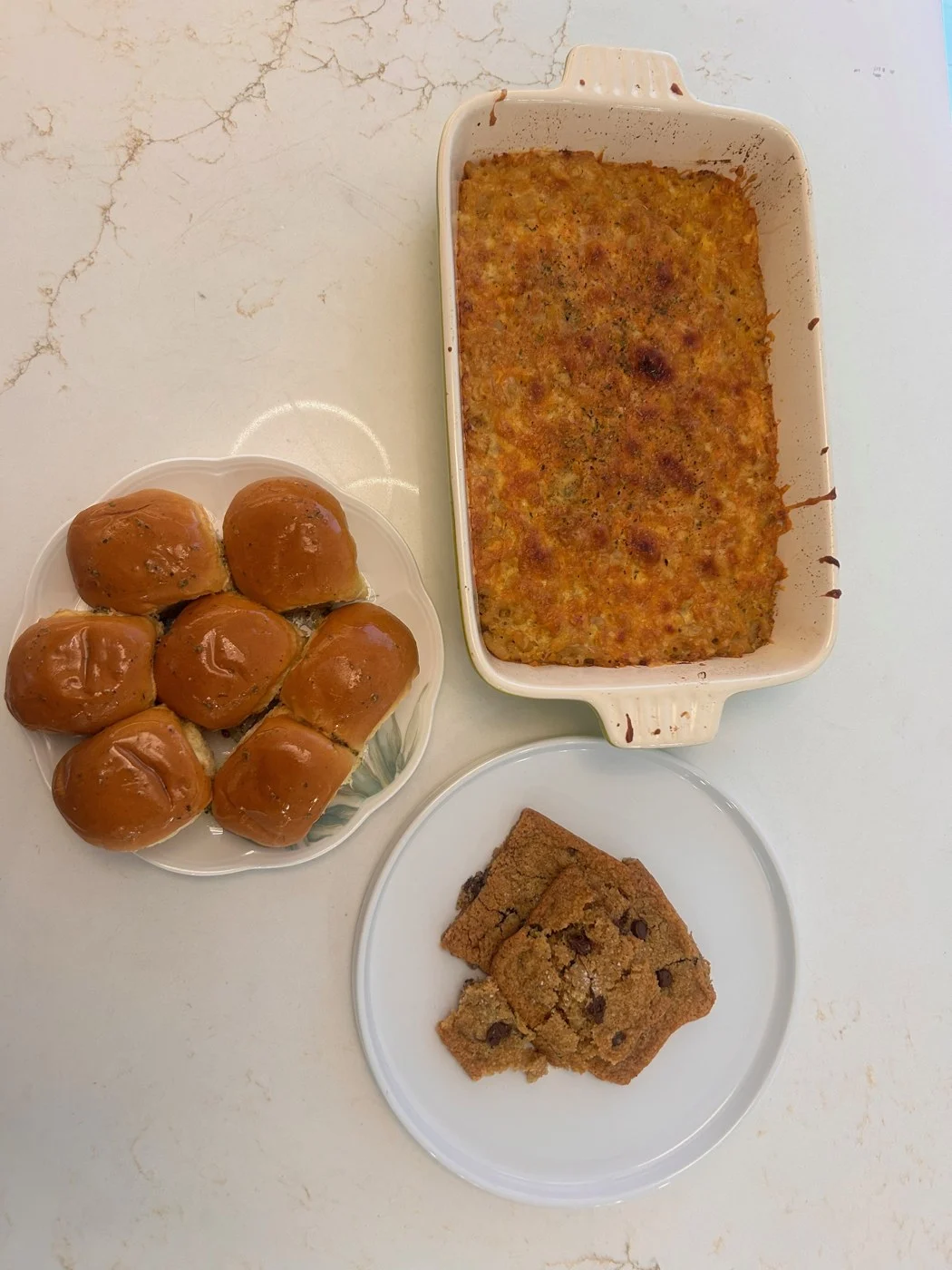 An overhead view of baked macaroni, golden rolls and chocolate-chip cookie pieces.