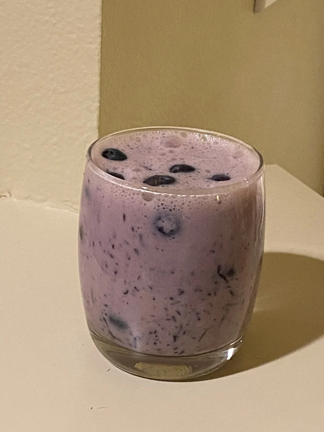 A purple speckled drink topped with whole blueberries.
