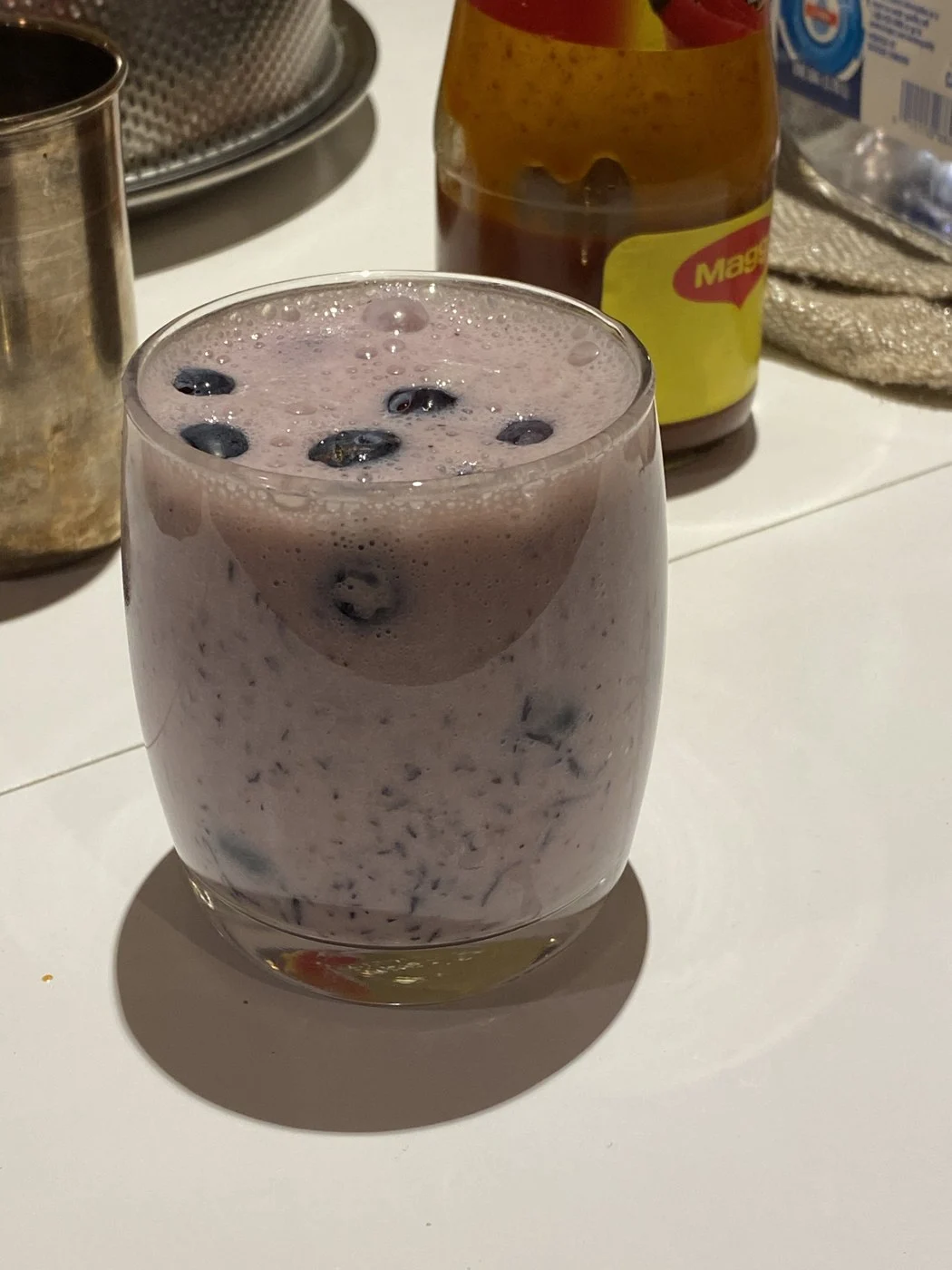 A glass of pale purple drink with blueberries floating on top.