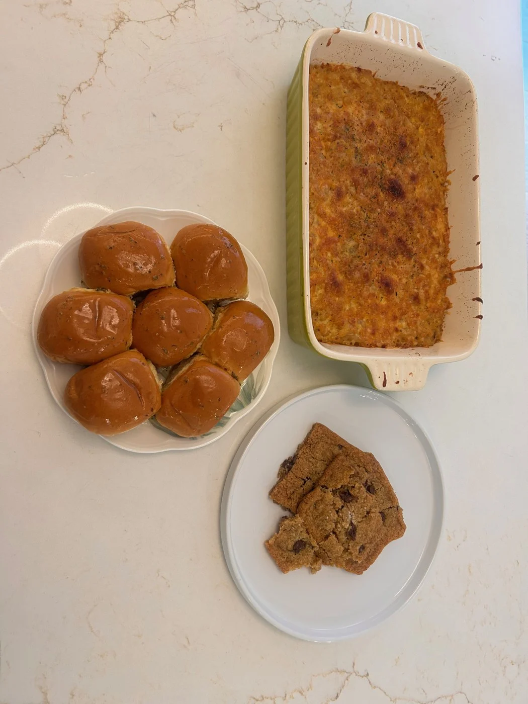 A dinner spread of browned baked macaroni, shiny rolls and chocolate-chip cookie pieces.