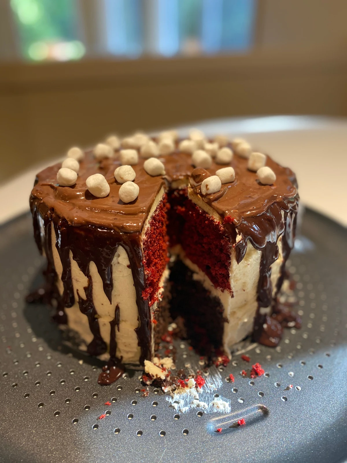 Another view of the cut drip cake, with pale frosting between red and dark layers.