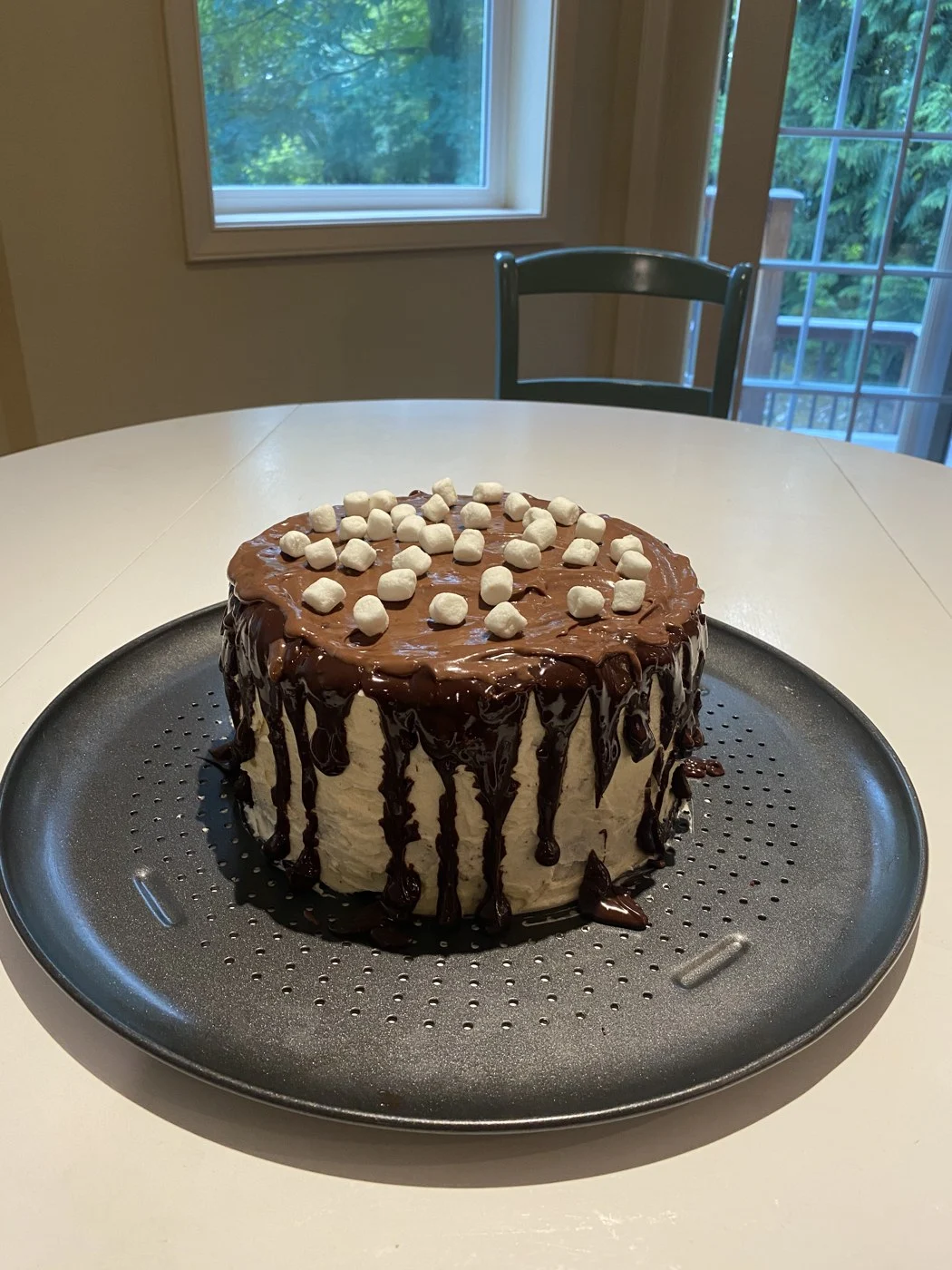 A finished chocolate-drip cake topped with small white marshmallows.