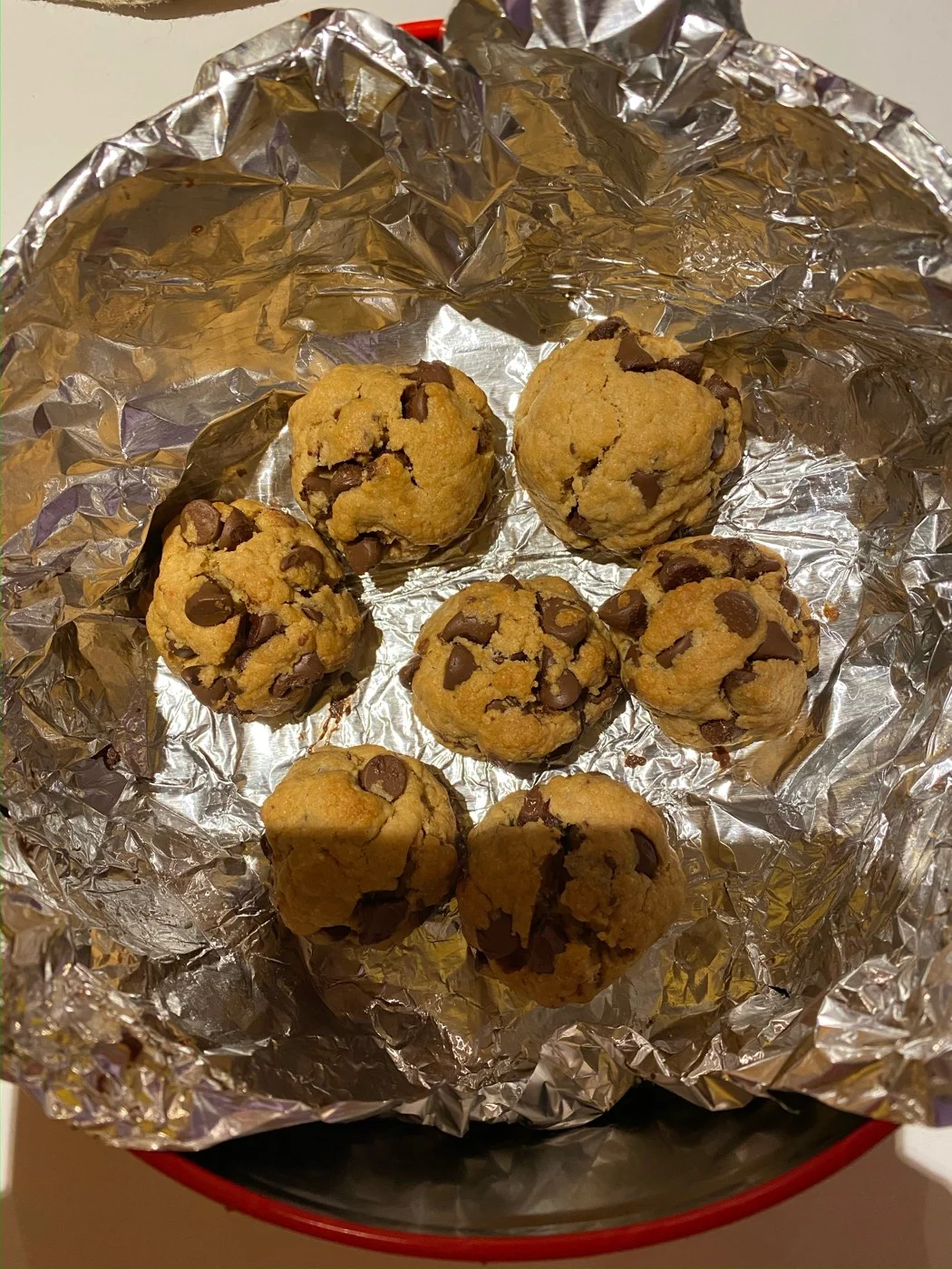 A tray of seven thick chocolate-chip cookies with rounded cracked tops.