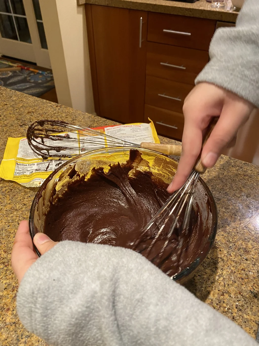 Whisking a thick chocolate mixture in a glass bowl.