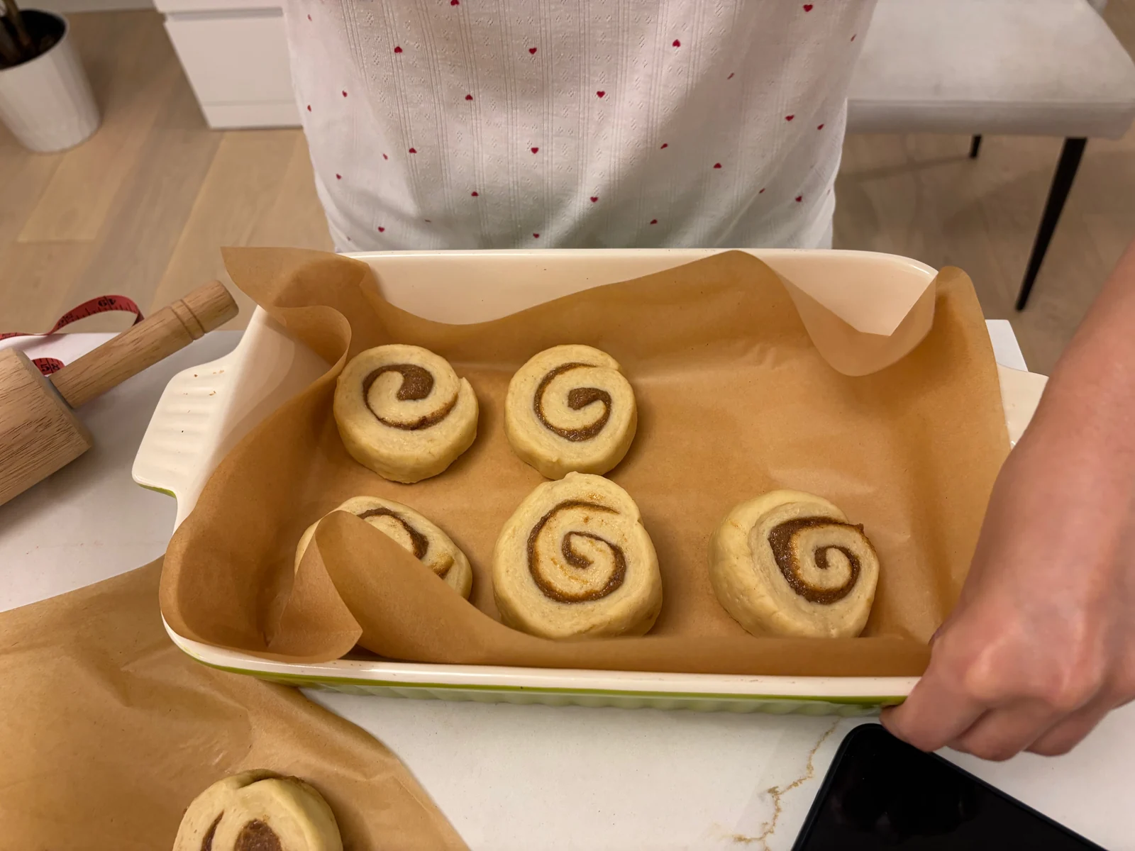 Cut spiral rolls spaced in a parchment-lined rectangular ceramic dish.