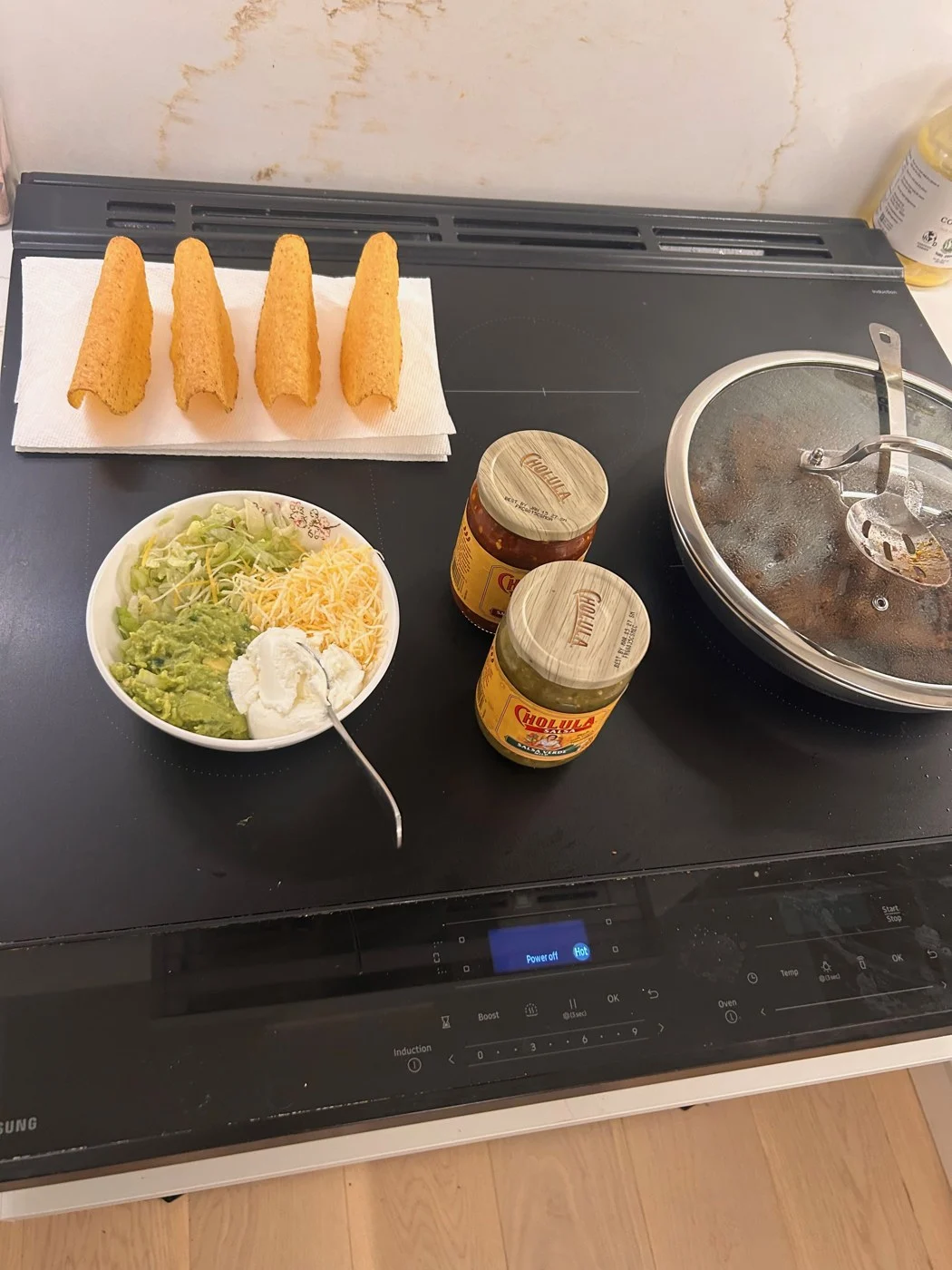 Empty crunchy taco shells with bowls of toppings and jars of sauce ready for assembly.