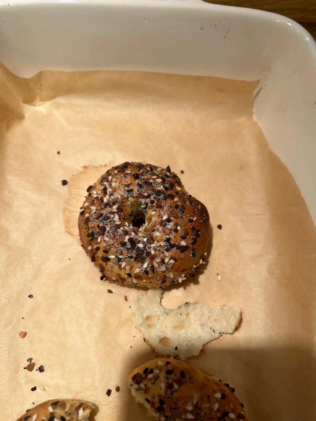 Seed-covered baked bread bites on parchment, with pale filling visible nearby.
