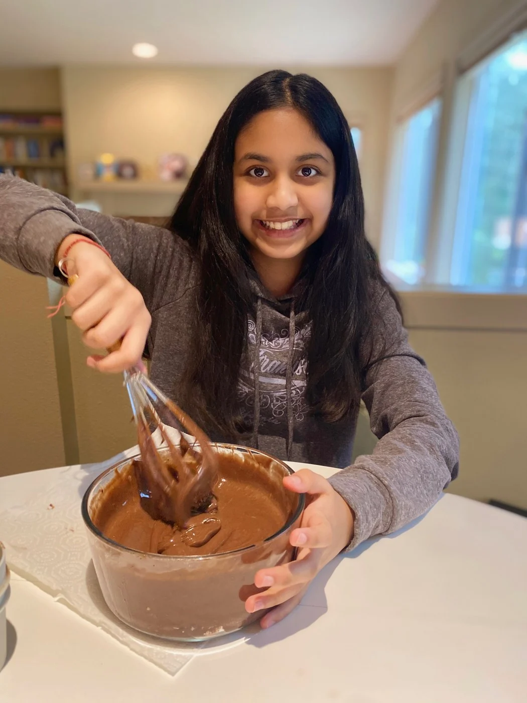 Stirring a bowl of chocolate batter at a white table.
