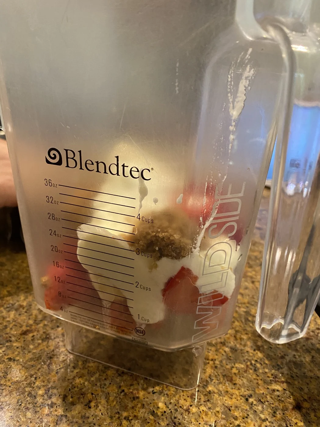 Strawberries, banana pieces and pale ingredients in a blender jar before blending.