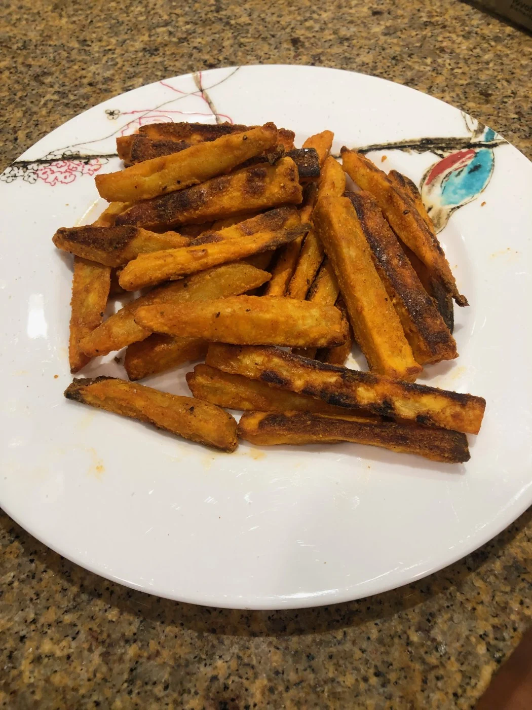 Roasted orange sweet-potato fries piled on a white plate.