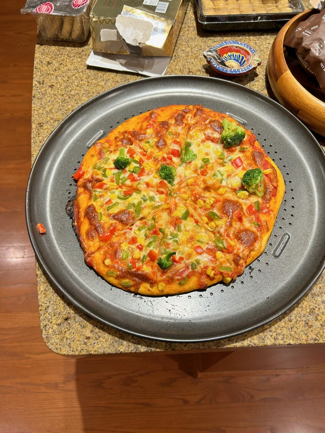 A baked pizza with golden cheese and chopped peppers on a round tray.
