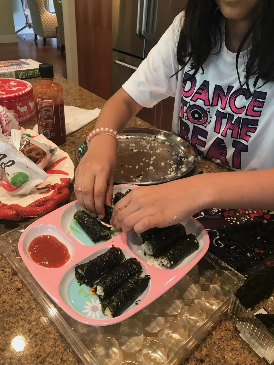 Filling and arranging seaweed-wrapped rice rolls on a divided plate.