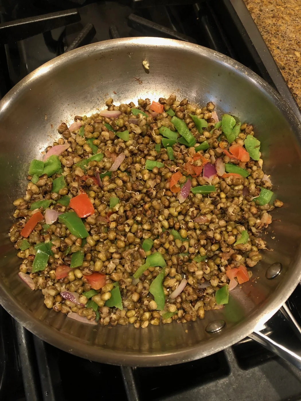 Small whole green legumes with chopped vegetables and herbs in a frying pan.